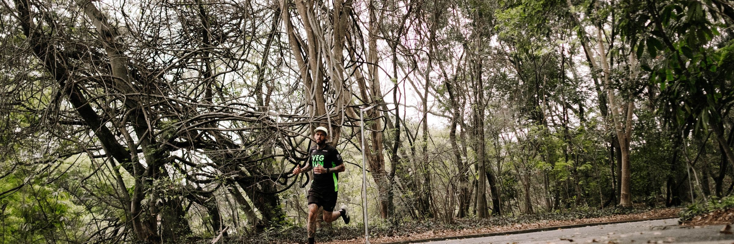 Felipe pequeno no meio de árvores retorcidas, correndo numa pista do parque
